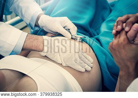 The Doctor Wears White Gloves Using A Stethoscope To Check The Pregnancy Of The Girl. Husband Shook 