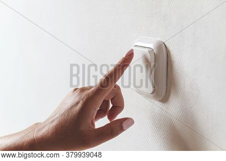 Female Hand Turns Off The Light Indoors. Electrical Energy Savin