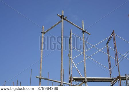 The Steel Scaffolding With Brown Rust Standing On The Top Floor Of The Building Under Blue Sky