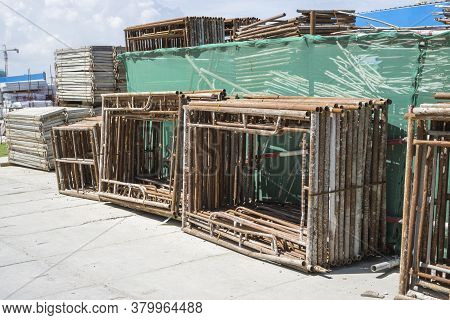 A Pile Of Steel Scaffolding With Brown Rust On The Cocrete Floor In Front The Building