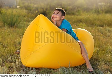 Boy In A Blue T-shirt, Sitting On A Yellow Lamzak, In Nature, The Concept Of Summer
