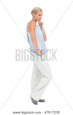 Blonde vrouw die lacht met hand op hip op witte achtergrond