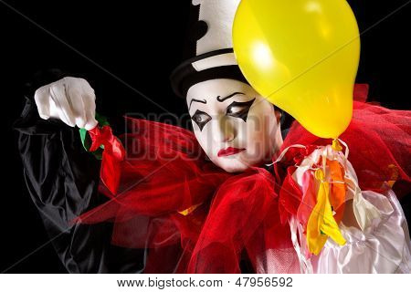Traurigen Pierrot Clown hält die Überbleibsel von seiner Ballons