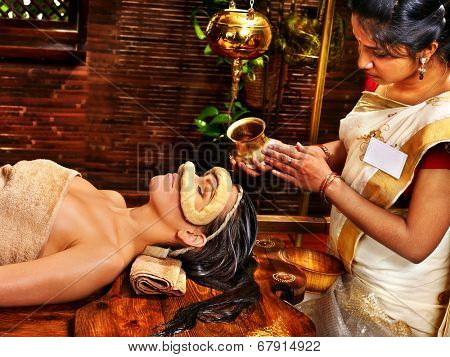 Woman having facial oil eyes mask at ayurveda spa.
