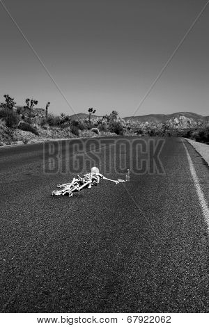 A lost hiker dies of thirst on a deserted desert road inches away from a bottle of water.  Dark Humor Series. In Black and White