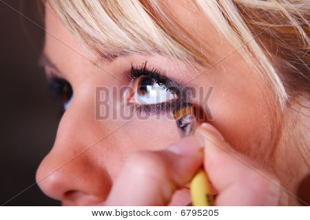 Maquiador aplicando sombra na face de uma jovem mulher