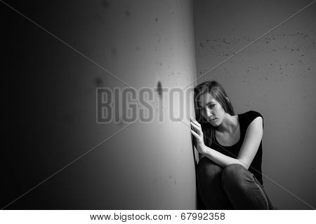 Young woman suffering from a severe depression (very harsh lighting is used on this shot to underline/convey the gloomy mood of the scene)