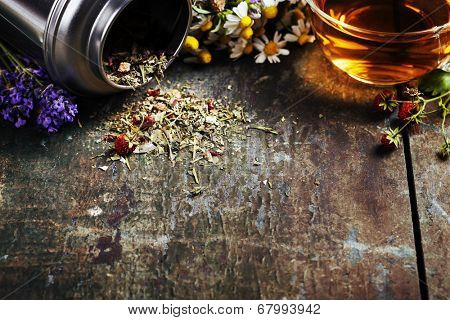 Herbal tea and wild organic flowers on wooden background