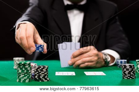 casino, gambling, poker, people and entertainment concept - close up of poker player with playing cards and chips at green casino table