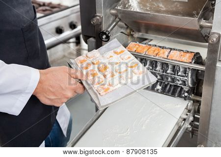 Midsection of male chef processing ravioli pasta in automated machine at commercial kitchen