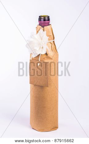 bottle wrapped in paper with white flower and blank card