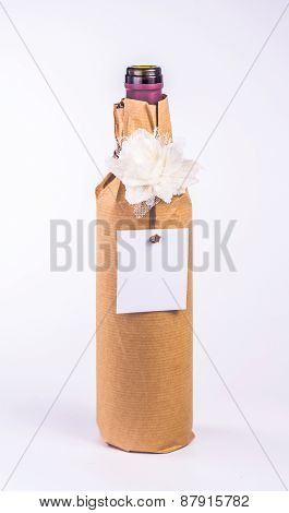 isolated bottle wrapped in paper with white flower and card