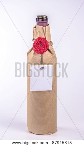 bottle wrapped in paper with red flower and blank card
