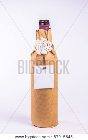 isolated bottle wrapped in paper with white flower and card