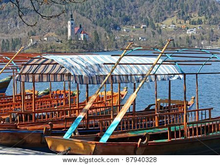 Rowboats Moored On The Shore Of Lake Bled In Slovenia And The Church