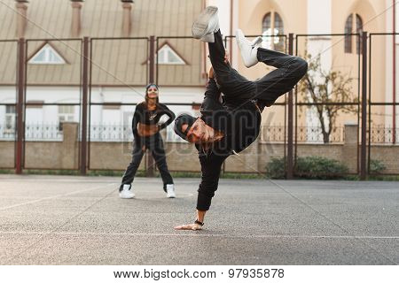 Handsome Guy In A Stylish Black Clothes Dancing Hip-hop. Dancer Standing On His Hand. The Girl