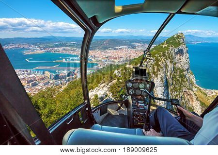 Aerial view of top of Gibraltar Rock. Gibraltar is a territory of South West Europe which is part of the United Kingdom. Helicopter cockpit with pilot arm and control console inside the cabin.