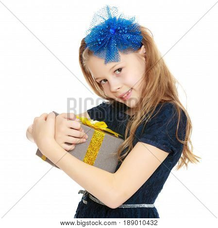 Cute Caucasian little girl In a dark blue dress and big blue bow on her head. The girl holds box with gift.Isolated on white background.