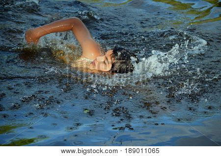 Young Argentine man is training swimming in a lake of the province of Cordova, Argentina