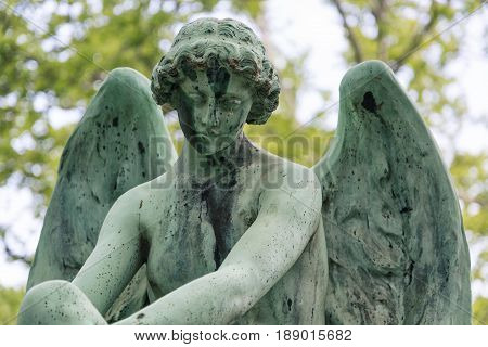 Young angel sculpture on a tomb at a graveyard.