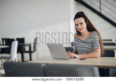 Charming young female owner of business calling to manager supervising work of employee sitting in cafe interior, businesswoman having phone conversation with banking service making money transfer.