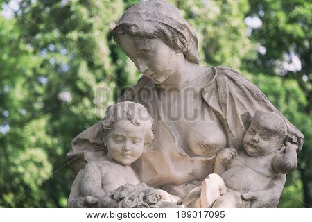 Young mother with little children monument on a tomb at a graveyard.