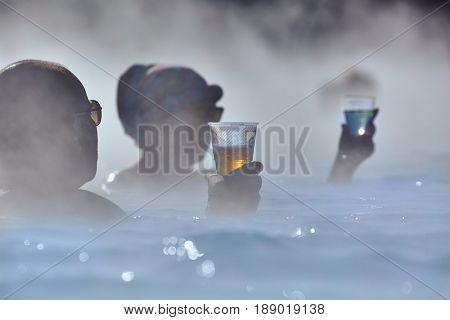 GRINDAVIK, ICELAND - MAY 04, 2015: People in popular Blue Lagoon thermal bath in Iceland. You can buy drinks at the bar while soaking in the steaming water.