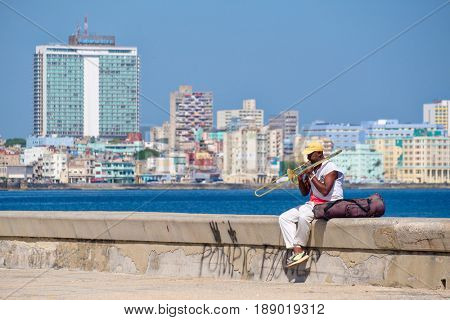 HAVANA,CUBA - MAY 29, 2017 : A street musician plays the trombone at the famous seaside Malecon wall in Havana