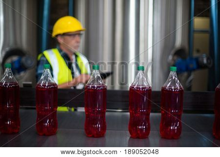 Male factory worker monitoring cold drink bottles at drinks production factory