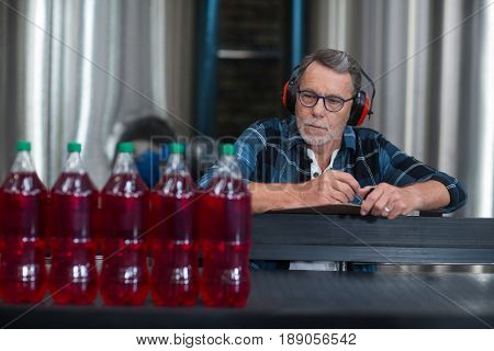 Male factory worker monitoring cold drink bottles at drinks production factory