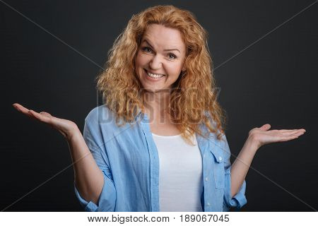 You couldnt guess that. Bright engaging active woman using her hands for expressing her feelings better while standing isolated on grey background