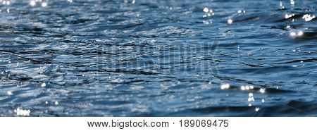 Water with bokeh background. Water surface with waves glittering in the sun. Banner for website.