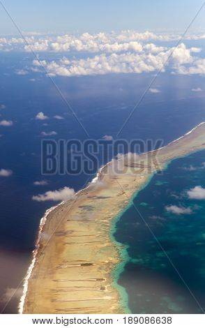 Polynesia. The atoll in ocean through clouds. Aerial view.