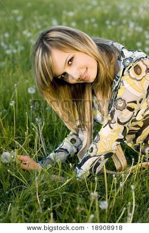 Een mooi jong meisje ontspannen op een weide met paardebloemen