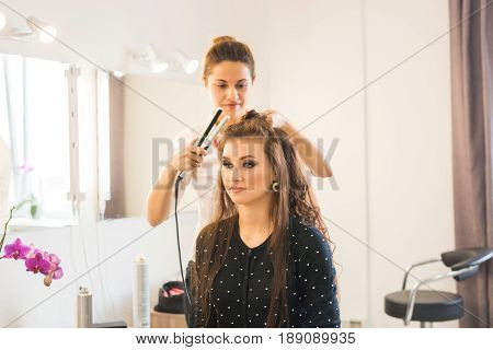 working day inside the beauty salon. Hairdresser makes hair styling.