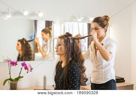 working day inside the beauty salon. Hairdresser makes hair styling.