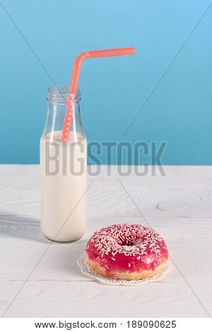 Glass Bottle Of Milk With Donut On Plate On Blue Background