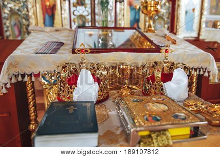 Golden wedding crowns with precious stones lying on the table in the church
