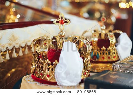 Golden wedding crowns with precious stones lying on the table in the church