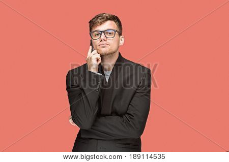 The young caucasian businessman in glasses on red studio background talking on cell phone