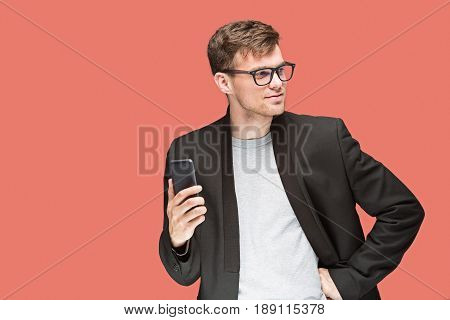 The young caucasian businessman in glasses on red studio background talking on cell phone