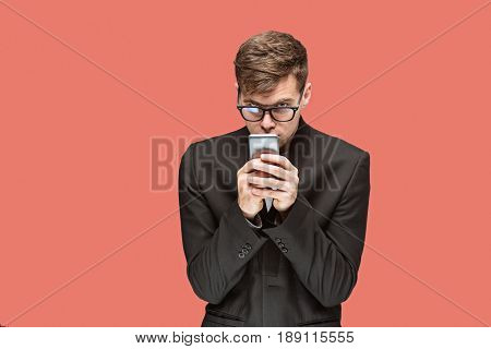 The young caucasian businessman in glasses on red studio background talking on cell phone