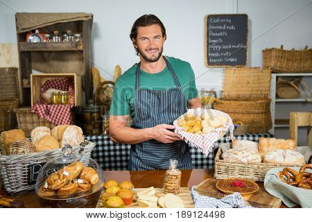 Portrait of staff holding bakery snacks at counter in bakery shop