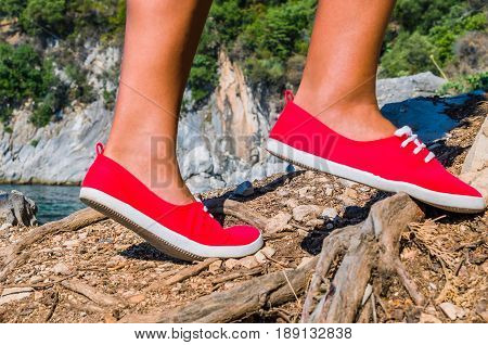 Close up of a tourist girl feet wearing red shoes hiking on cefalonia island, mediterranean, greece.