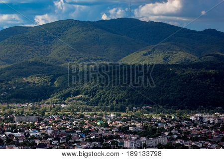 little town on a plain surrounded by mountains green hills. summer sunny landscape. view from the mountain