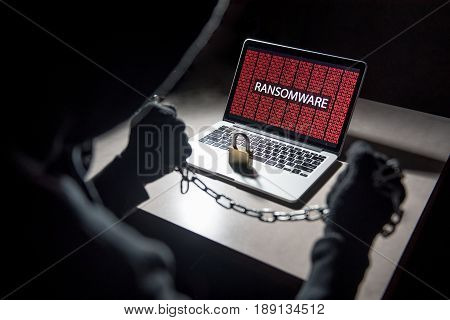Male hacker locking computer by using chain and padlock malware ransomware Trojan concept. Internet security concept