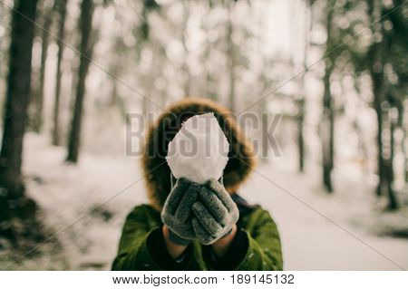 Woman holding a snowball in the forest. Playing with the snow. Winter games. Snowball in hand. 