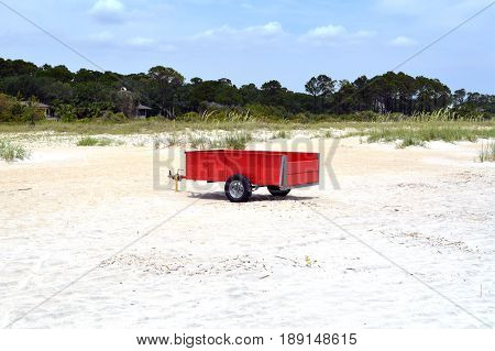 Bright red cart sits in sand on beach