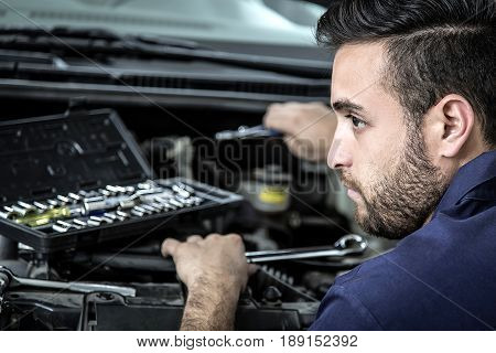 Car Mechanic Man At The Garage Fixing The Engine