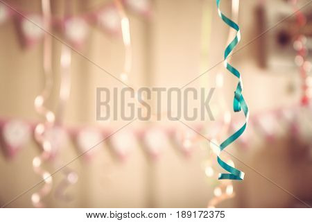 Vintage happy birthday party defocused background with hanging ribbons and garland in decoarated room in pastel colors